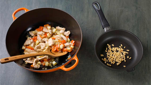 Fres grønnsaker i olje i ca. 4 min, tilsett kylling og stek til den er gjennomstekt, ca. 5 min. Rist pinje-kjerner i tørr stekepanne til de er gylne, ca. 3 min.
