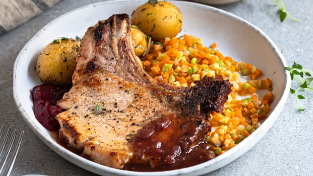 Server koteletter med lune grønnsaker, poteter og saus.