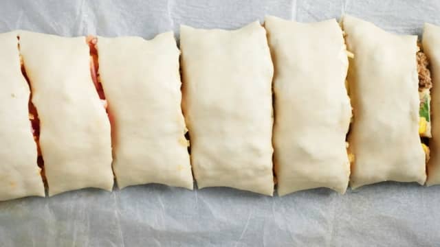 Rull sammen pizzadeigen til en lang pølse. Kutt pizzarullen i 3 cm tykke skiver.