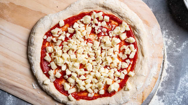 Ha på mozzarella. Osten skal ikke dekke hele sausen, for mye ost vil gjøre at pizzabunnen ikke blir ordentlig sprø.