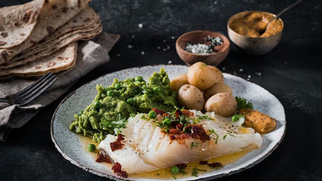 Server lutefisken med kokte mandelpoteter, ertepurè og sennepsaus. Topp fisken med sprøstekt bacon og baconfett.