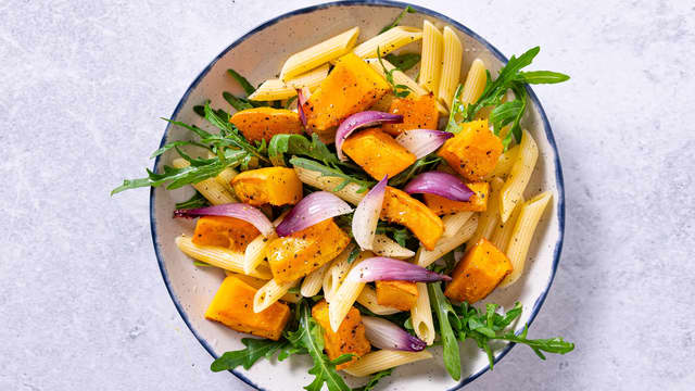 Anrett salaten med pasta, gresskar, rødløk og ruccula og topp med en skvis av den bakte sitronen.