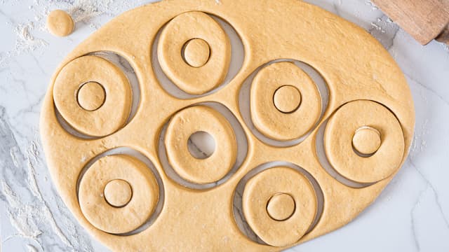 Stikk ut sirkler i deigen. Bruk gjerne store utstikkerringer eller et glass. Stikk deretter ut en mindre sirkel inni den store sirkelen, enten med en mindre utstikkerring eller et mindre glass.