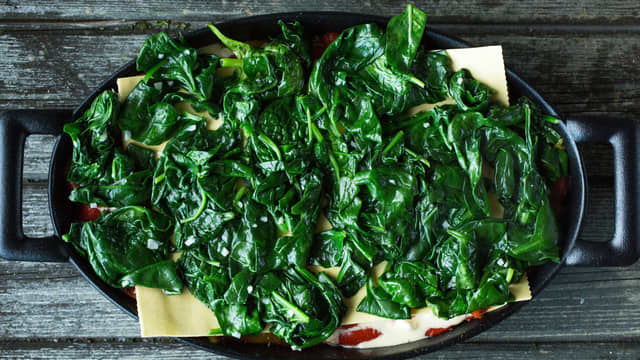 Når du fyller formen starter du med hvit saus. Fortsett med lasagneplater, spinat, løk og tomater – og gjenta