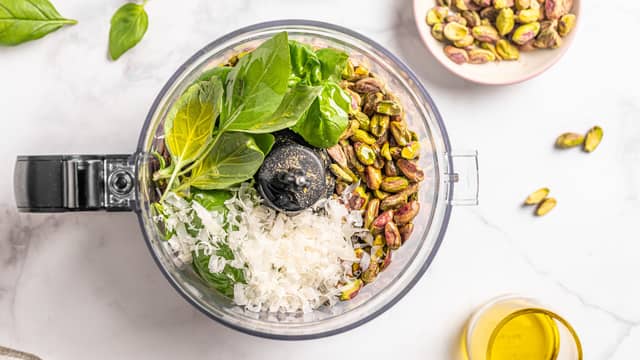Ha pistasjnøtter, parmesan, hvitløk og basilikum i en foodprosessor. Kjør til en grov masse.