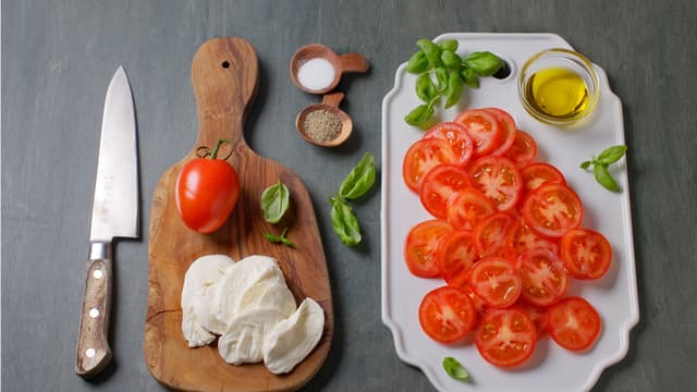 Skjær tomater og mozzarella i skiver og anrett med basilikumblader på et fat og drypp over olivenolje. Server kyllingboller med dressing og tomatsalat.