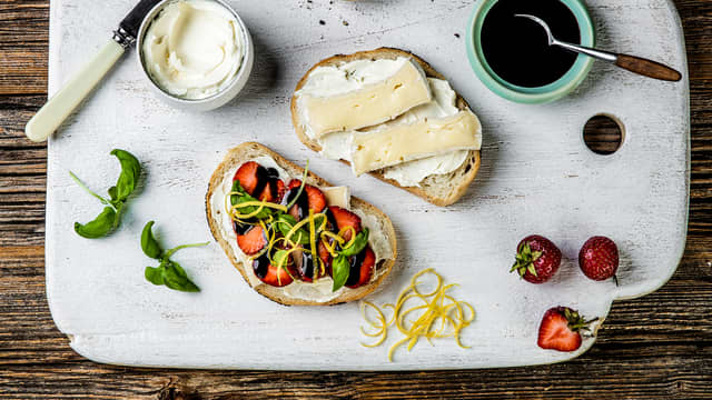 Legg to skiver brie på den ene skiven og topp med skivede jordbær, basilikum, balsamicoeddik og revet sitronskall.