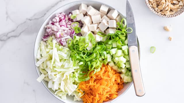 Skjær tofu i terninger og ha det i en stor bolle med alle grønnsakene.
