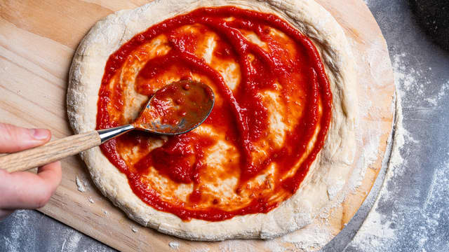 Dekk pizzabunnene med et tynt lag pizzasaus. Skjær rødløk i skiver.