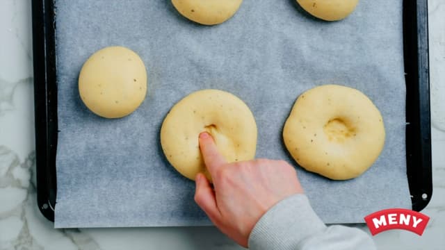 Sett bollene på en stekeplate dekket med bakepapir og trykk dem litt ned på midten. Sett dem til heving under et kjøkkenhåndkle i ca 20-30 minutter eller til du ser at bollene har blitt store og fine.