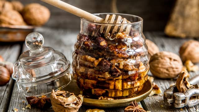 Hakk nøttene, bland med honningen og ha over camemberten. Server mens den enda er lun.