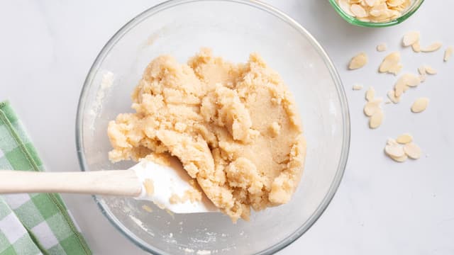 Ha mandelmel, sukker, mel og eggehviter i en bolle. Bland alt sammen med en slikkepott til du har en jevn og litt klissete deig.