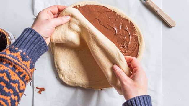 Legg en sirkel på et bakeark. Smør på med sjokoladepålegg, men la det være 1 cm i kanten uten fyll. Legg en ny sirkel oppå og repeter til du har fire lag, men ikke smør sjokoladepåleggpå det øverste laget.