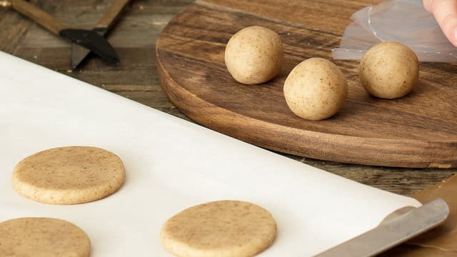Form deigen til kuler og legg dem på et bakebrett med bakepapir. Press kulene flate.