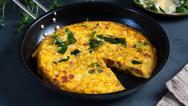 Når omeletten har blitt fast dekker du den med et lokk og snur opp ned slik at den havner på lokket. La den så gli ned i stekepannen med den stekte siden opp.