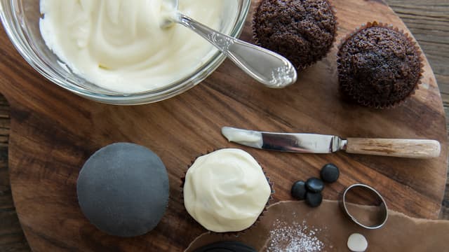 Pynte hund: Legg et tynt lag med kremostfrosting på cupcaken. Kjevle ut grå fondant, bruk
melis til å arbeide med fondanten.