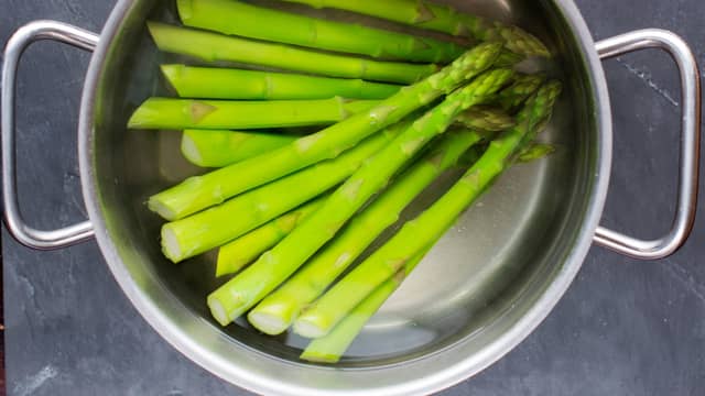 Kok aspargesen i lettsaltet vann til de akkurat er møre. Avkjøl raskt i kaldt vann. Kutt aspargesen i grove biter og vend inn pastaen med rødløk og hasselnøtter.