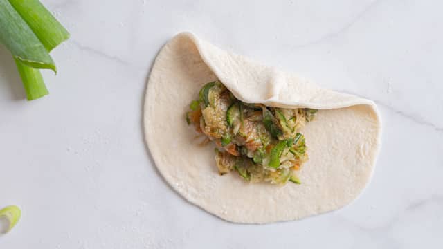 Kjevle ut hver bolle ut til en tynn sirkel. Legg 1 ss fyll på hver sirkel.