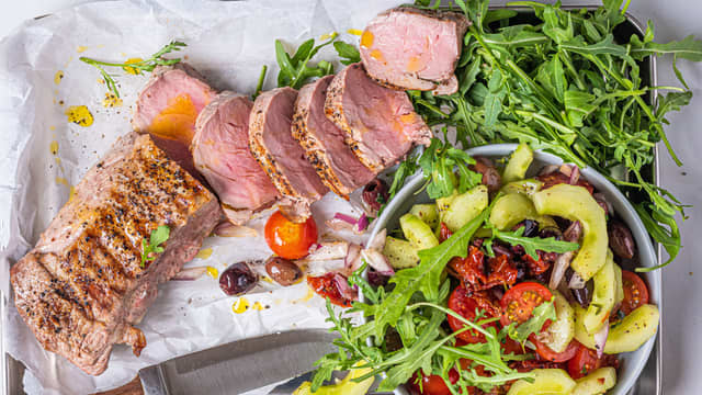 Server svinefileten på fat sammen med salaten og tzatziki.