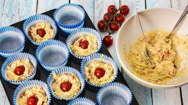 Fyll muffinsformene og stikk en cherrytomat ned i midten av hver muffin. **Stek dem på 210 grader i ca. 20 minutter**.