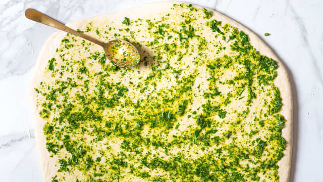 Fordel urteblandingen og revet ost utover deigen.