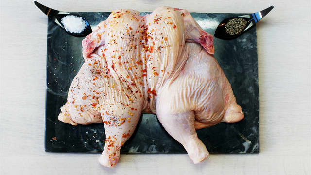 Dersom du har hel kylling, klipper du denne langs ryggbenet og bretter den ut. Gni kyllingen inn med olivenolje og krydder, og legg den på et stekebrett. Legg grønnsakene rundt kyllingen.