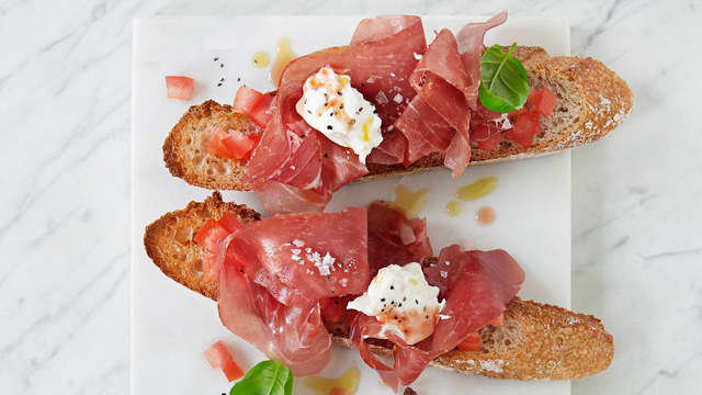 Fordel tomatene utover brødet. Legg på 2 skiver skinke på hver brødskive og en «dæsj» mozzarella. Ha over litt basilikum, olivenolje, salt og pepper på toppen!