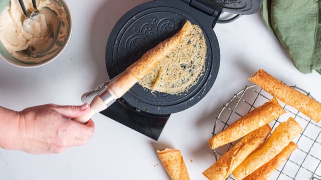 Kakene stekes gylne og formes til kremmerhus ved hjelp av en krumkakepinne.