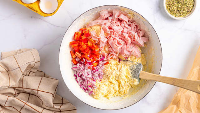 Kutt skinke i terninger eller strimler. Del paprika i små terninger og finhakk rødløken. Vend dette inn i røren sammen med revet ost.