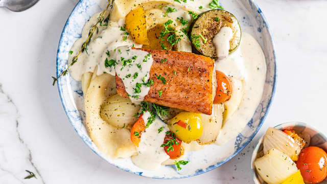 Anrett potetmos, ovnsbakte grønnsaker, laks og saus på to tallerkener.