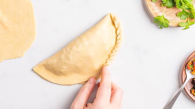 Brett sammen kanten rundt slik at du får en pen kant. Pensle empanadasene med egg og strø på sesamfrø.