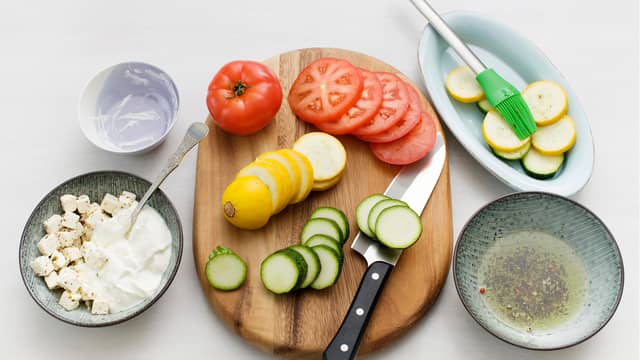 Hell oljen av fetaosten, og sett oljen til side. Mos osten med en gaffel og bland med yoghurten. Skjær tomater og squash i skiver og pensle med oljen fra fetaosten.