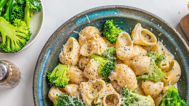 **Hell av vannet** til pastaen og vend inn ferdig ostesaus. Smak til med salt og pepper, og anrett pastaen med brokkolini og revet parmesan.