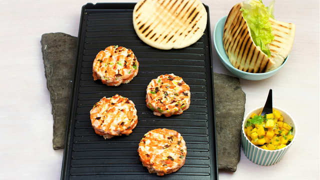 Varm pitabrødene på grillen eller i stekeovnen på 200 °C. Lag et snitt i brødene og fyll med salat, lakseburger og mangosalsa.