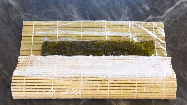 Rull bambusmatten stramt sammen til en fast rull.