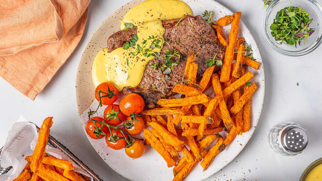 Server entrecôten med béarnaisesaus, søtpotetfries og lettstekt grønnkål.