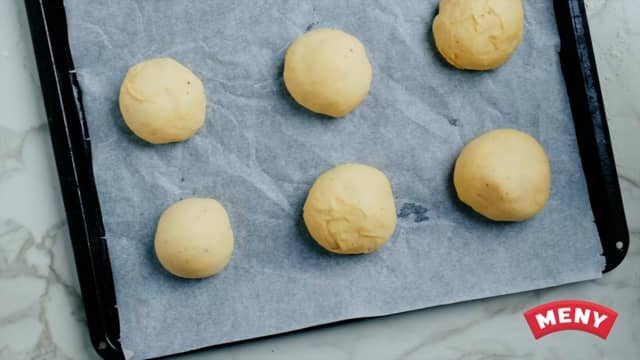 Hell deigen ut på bakebordet og del bollene opp i lik størrelse. Ikke tilsett mel dersom det ikke er behov for dette.  Trill runde boller, og la etterheve i 20 minutter i stekeovnen på 50 grader.