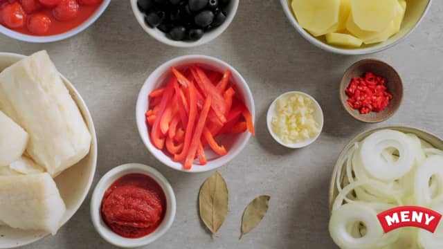 Bløtlegg klippfisken etter anvisningen på pakken. Skjær potet, løk og paprika i skiver, og finhakk chili og hvitløk.