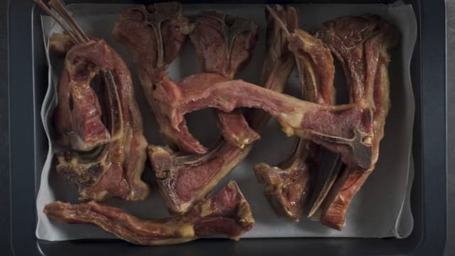 Ta pinnekjøttet opp fra kjelen, og ta vare på kraften. Pensle kjøttstykkene med flytende honning på begge sider og legg dem pent i en langpanne dekket med bakepapir. **Sett pinnekjøttet høyt i ovnen på grillfunksjon i 2-3 minutter** på hver side før servering.