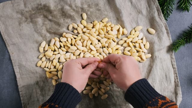 Legg mandlene på et kjøkkenhåndkle, brett over og kna mandlene litt. Da løsner skallet. Klem mandlene ut av skallet med fingrene.