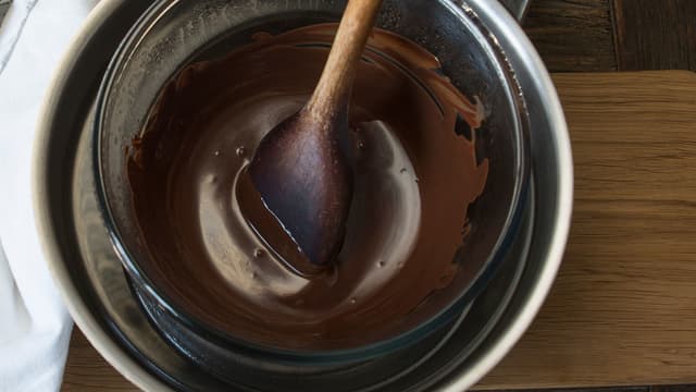 Smelt sjokoladen i vannbad. Rull kulene i sjokoladen og deretter i de finhakkede nøttene. Oppbevares kjølig.