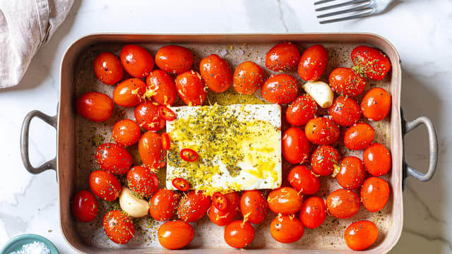Plasser fetaosten midt i formen. Ha over resten av oljen, saltet og pepperet. Dryss over oregano og sitronskall.