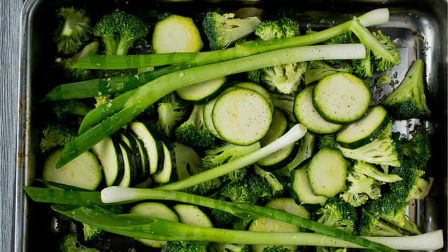 Rens og del brokkolien i små buketter og skjær squashen i skiver. Rens vårløken og bland alt sammen i en langpanne. Drypp over litt olje, krydre med litt salt og pepper og vend alt godt sammen.