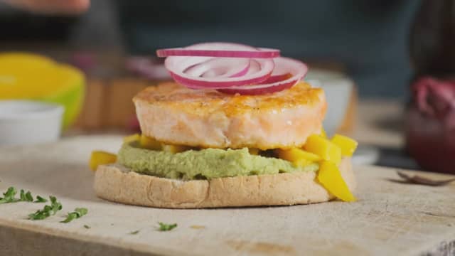 Ha guacamole på bunnen av burgerbrøene. Legg på salmaburgerne og topp med mango før du legger på burgertoppen.