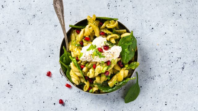 For kald pastasalat lar du pastaen avkjøle seg et par minutter før du blander inn pesto og spinat. Dander så med ricotta og granateplekjerner på toppen, som vist på bildet.