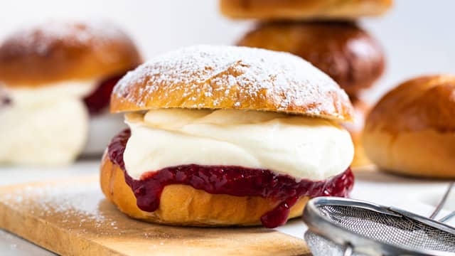 Del bollene i to og fyll dem med syltetøy og nypisket krem.