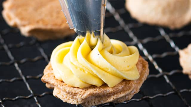 **Gule bomber:**  Her velger du om du pynter og serverer en og en mandeltopp med gul krem, eller om du legger en ny mandeltopp oppå den gule kremen.