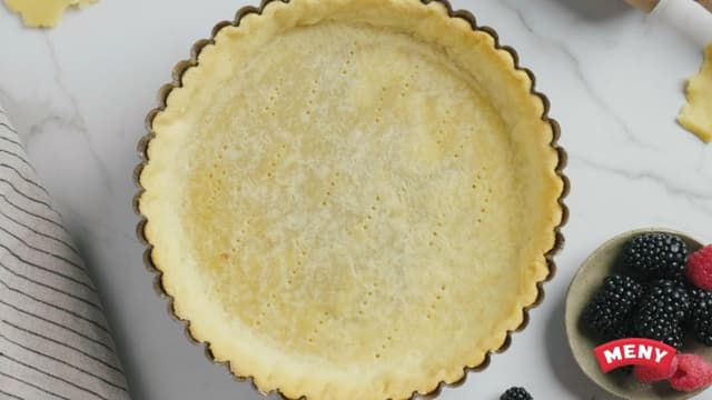 Pensle en terteform (ca. 30cm i diameter) med smør og press deigen utover bunn og kanter. Prikk bunnen med en gaffel.