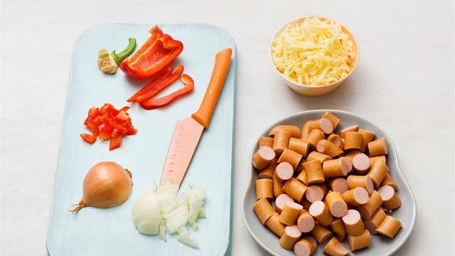 Rens og skjær grønnsakene i terninger. Riv ost og skjær pølsene i biter.