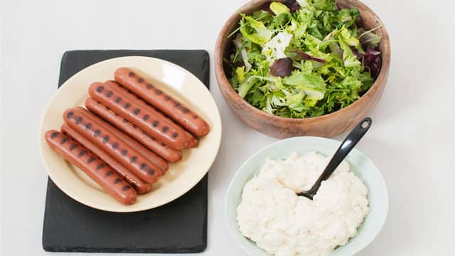 Anrett salaten på serveringsfat, topp med pølsebiter og saus, og server.